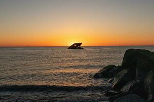 Sunset beach in Cape May New Jersey where you can get a great view of the sun going down across the ocean and the bay. The reflection of the sun on the water with the sunken ship looks so beautiful. photo
