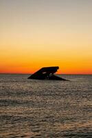 Sunset beach in Cape May New Jersey where you can get a great view of the sun going down across the ocean and the bay. The reflection of the sun on the water with the sunken ship looks so beautiful. photo