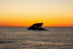 Sunset beach in Cape May New Jersey where you can get a great view of the sun going down across the ocean and the bay. The reflection of the sun on the water with the sunken ship looks so beautiful. photo