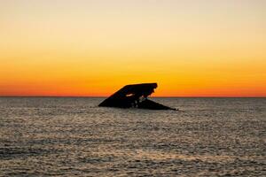 Sunset beach in Cape May New Jersey where you can get a great view of the sun going down across the ocean and the bay. The reflection of the sun on the water with the sunken ship looks so beautiful. photo