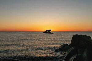 Sunset beach in Cape May New Jersey where you can get a great view of the sun going down across the ocean and the bay. The reflection of the sun on the water with the sunken ship looks so beautiful. photo