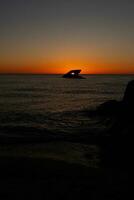 Sunset beach in Cape May New Jersey where you can get a great view of the sun going down across the ocean and the bay. The reflection of the sun on the water with the sunken ship looks so beautiful. photo