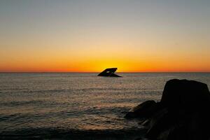 Sunset beach in Cape May New Jersey where you can get a great view of the sun going down across the ocean and the bay. The reflection of the sun on the water with the sunken ship looks so beautiful. photo