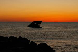 Sunset beach in Cape May New Jersey where you can get a great view of the sun going down across the ocean and the bay. The reflection of the sun on the water with the sunken ship looks so beautiful. photo