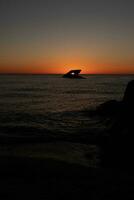 Sunset beach in Cape May New Jersey where you can get a great view of the sun going down across the ocean and the bay. The reflection of the sun on the water with the sunken ship looks so beautiful. photo