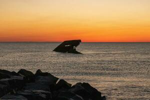 Sunset beach in Cape May New Jersey where you can get a great view of the sun going down across the ocean and the bay. The reflection of the sun on the water with the sunken ship looks so beautiful. photo