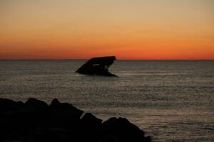 Sunset beach in Cape May New Jersey where you can get a great view of the sun going down across the ocean and the bay. The reflection of the sun on the water with the sunken ship looks so beautiful. photo