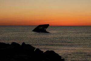 Sunset beach in Cape May New Jersey where you can get a great view of the sun going down across the ocean and the bay. The reflection of the sun on the water with the sunken ship looks so beautiful. photo