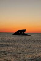 Sunset beach in Cape May New Jersey where you can get a great view of the sun going down across the ocean and the bay. The reflection of the sun on the water with the sunken ship looks so beautiful. photo