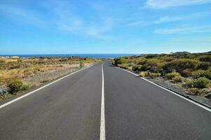 an empty road with a blue sky and ocean in the background photo