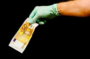 a hand in a glove holding a euro bank note photo