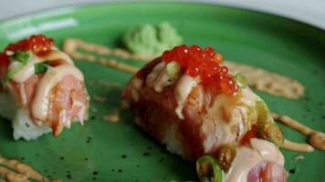 Japonais culinaire encore vie. Nigiri Sushi avec grillé thon et riz sur vert assiette à maison. rouge caviar sur le Haut de rouleau video
