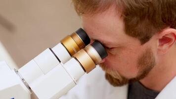 Ultra Macro Close Up Footage of a Male Scientist Wearing Medical Mask and Looking into the Microscope. Microbiologist Working on Molecule Samples in Modern Laboratory with Technological Equipment. video