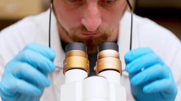 Ultra Macro Close Up Footage of a Male Scientist Wearing Medical Mask and Looking into the Microscope. Microbiologist Working on Molecule Samples in Modern Laboratory with Technological Equipment. video