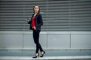 hermosa mujer yendo a trabajo con café caminando cerca oficina edificio. foto