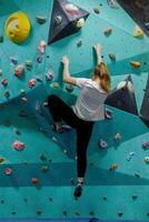 joven mujer alpinismo arriba en práctica pared en gimnasio foto