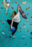 Young woman climbing up on practice wall in gym photo