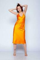 Portrait of attractive girl in orange dress in the studio photo