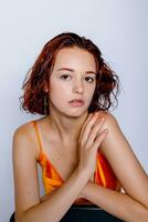 Portrait of attractive girl in orange dress in the studio photo