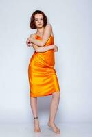 Portrait of attractive girl in orange dress in the studio photo