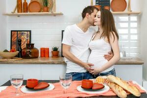 joven casado Pareja abraza en pie cerca mesa en cocina. foto