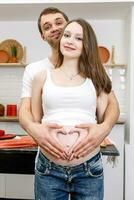 Young married couple embraces standing near table in kitchen. photo