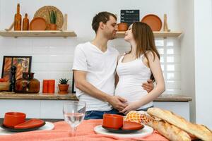 joven casado Pareja abraza en pie cerca mesa en cocina. foto