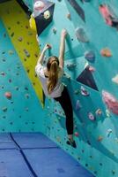 joven mujer alpinismo arriba en práctica pared en gimnasio foto