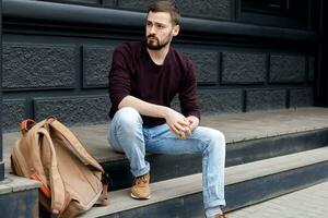 Happy young guy with beard relaxing with modern device outdoors photo