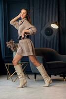 Young beautiful brunette woman in beige boots in a beautiful interior photo