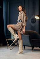 Young beautiful brunette woman in beige boots in a beautiful interior photo