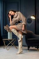 Young beautiful brunette woman in beige boots in a beautiful interior photo