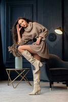 Young beautiful brunette woman in beige boots in a beautiful interior photo