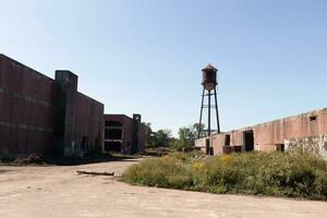 I love the look of this abandoned village. All of the roads are breaking down. The brick buildings all around are without windows and some have graffiti. The water tower in the distance is rusty. photo