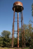 un hermosa agua torre es conjunto alrededor un abandonado área. esta oxidado metal estructura soportes alto en contra un azul cielo. foto