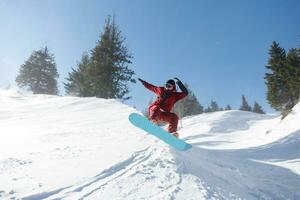 Active snowboarder jumping in mountains on a sunny day photo