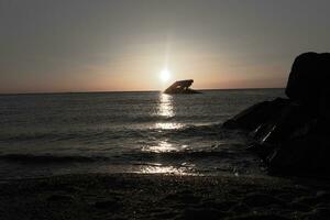 Sunset beach in Cape May New Jersey where you can get a great view of the sun going down across the ocean and the bay. The reflection of the sun on the water with the sunken ship looks so beautiful. photo