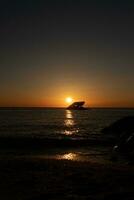 Sunset beach in Cape May New Jersey where you can get a great view of the sun going down across the ocean and the bay. The reflection of the sun on the water with the sunken ship looks so beautiful. photo