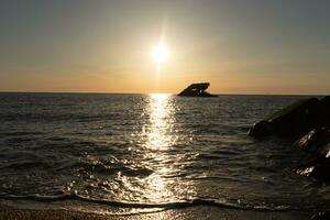Sunset beach in Cape May New Jersey where you can get a great view of the sun going down across the ocean and the bay. The reflection of the sun on the water with the sunken ship looks so beautiful. photo