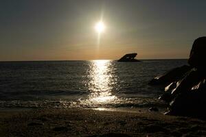 Sunset beach in Cape May New Jersey where you can get a great view of the sun going down across the ocean and the bay. The reflection of the sun on the water with the sunken ship looks so beautiful. photo