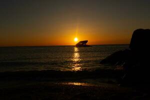 Sunset beach in Cape May New Jersey where you can get a great view of the sun going down across the ocean and the bay. The reflection of the sun on the water with the sunken ship looks so beautiful. photo