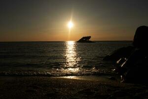 Sunset beach in Cape May New Jersey where you can get a great view of the sun going down across the ocean and the bay. The reflection of the sun on the water with the sunken ship looks so beautiful. photo