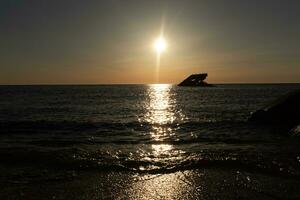 Sunset beach in Cape May New Jersey where you can get a great view of the sun going down across the ocean and the bay. The reflection of the sun on the water with the sunken ship looks so beautiful. photo