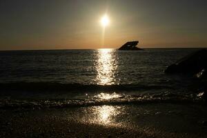 Sunset beach in Cape May New Jersey where you can get a great view of the sun going down across the ocean and the bay. The reflection of the sun on the water with the sunken ship looks so beautiful. photo