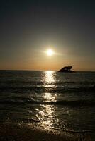 Sunset beach in Cape May New Jersey where you can get a great view of the sun going down across the ocean and the bay. The reflection of the sun on the water with the sunken ship looks so beautiful. photo