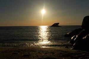 puesta de sol playa en capa mayo nuevo jersey dónde usted lata obtener un genial ver de el Dom yendo abajo a través de el Oceano y el bahía. el reflexión de el Dom en el agua con el hundido Embarcacion mira entonces hermosa. foto