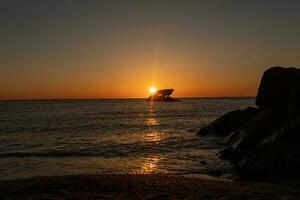 Sunset beach in Cape May New Jersey where you can get a great view of the sun going down across the ocean and the bay. The reflection of the sun on the water with the sunken ship looks so beautiful. photo