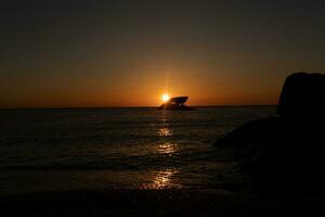 Sunset beach in Cape May New Jersey where you can get a great view of the sun going down across the ocean and the bay. The reflection of the sun on the water with the sunken ship looks so beautiful. photo