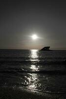 Sunset beach in Cape May New Jersey where you can get a great view of the sun going down across the ocean and the bay. The reflection of the sun on the water with the sunken ship looks so beautiful. photo