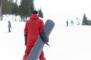 Snowboarder in helmet standing at the very top of a mountain photo